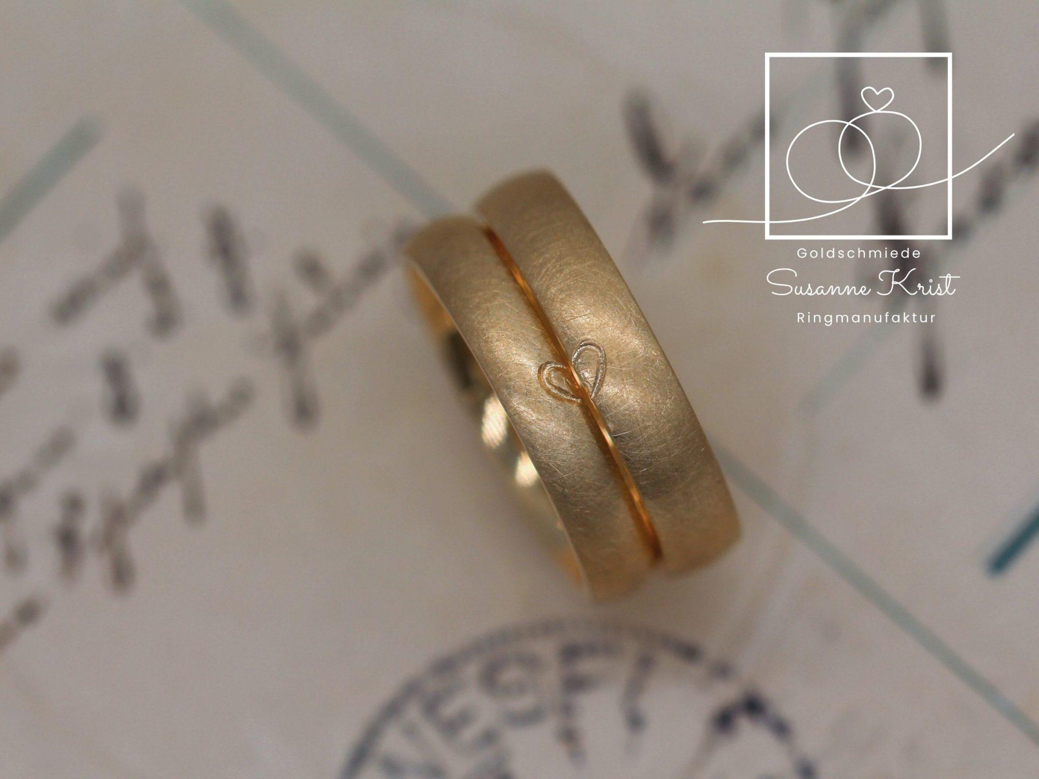 Matte Trauringe aus Gold mit Herzhälften.
